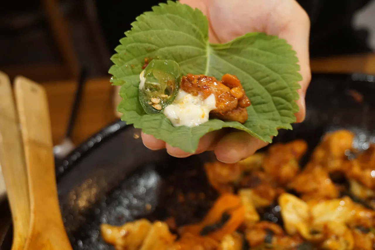 깻잎에 직화 닭갈비를 싸서 먹는 모습